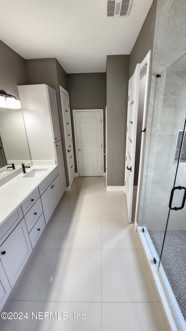 bathroom featuring tile patterned flooring, vanity, and a shower with door