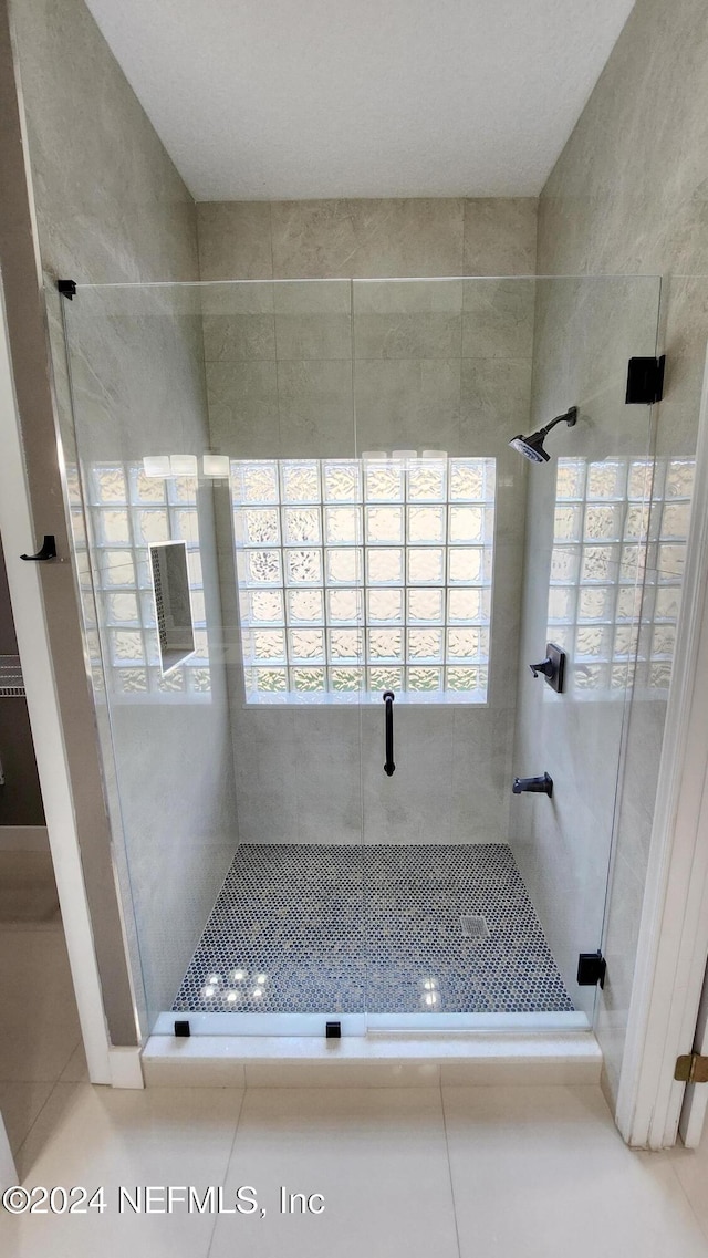 bathroom featuring a wealth of natural light, tile patterned flooring, and an enclosed shower