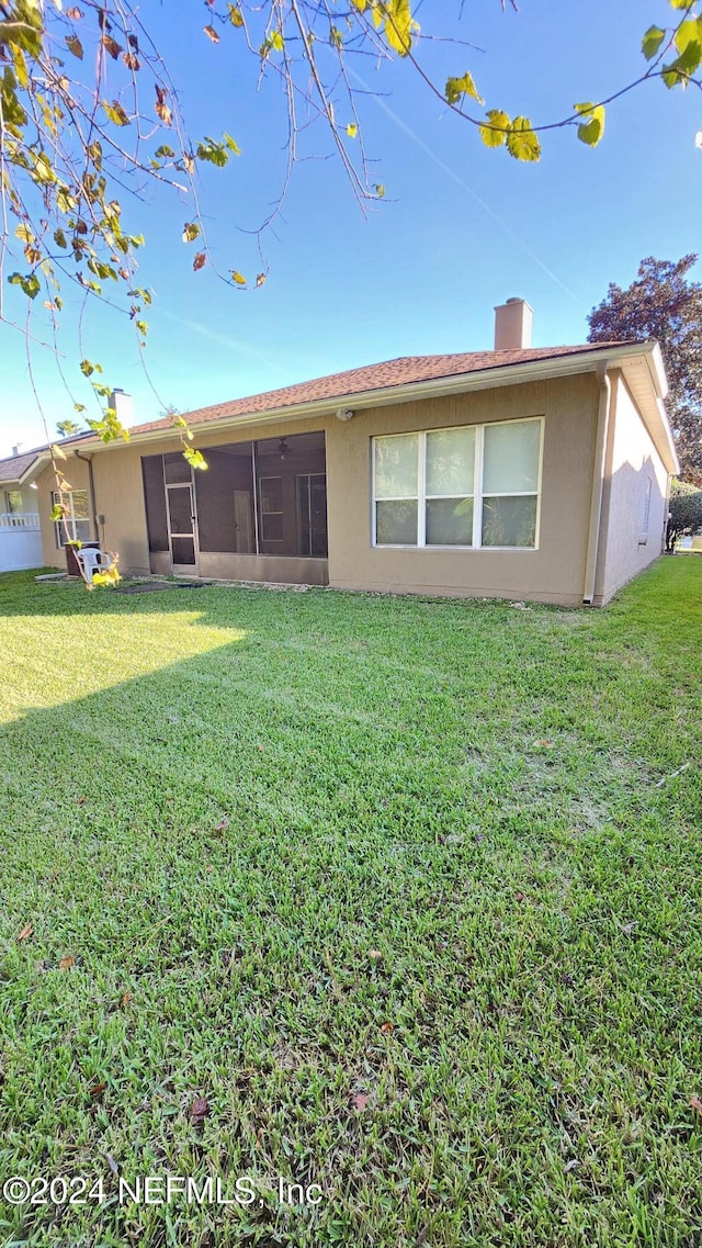 rear view of house featuring a sunroom and a lawn