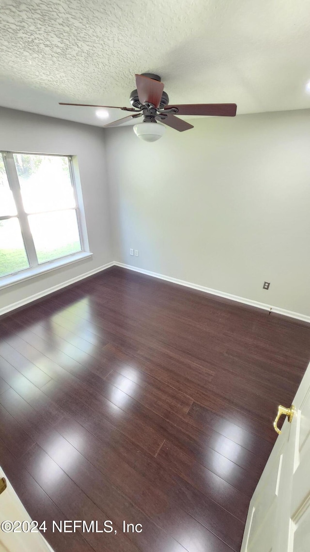 unfurnished room featuring a textured ceiling, dark hardwood / wood-style floors, and ceiling fan