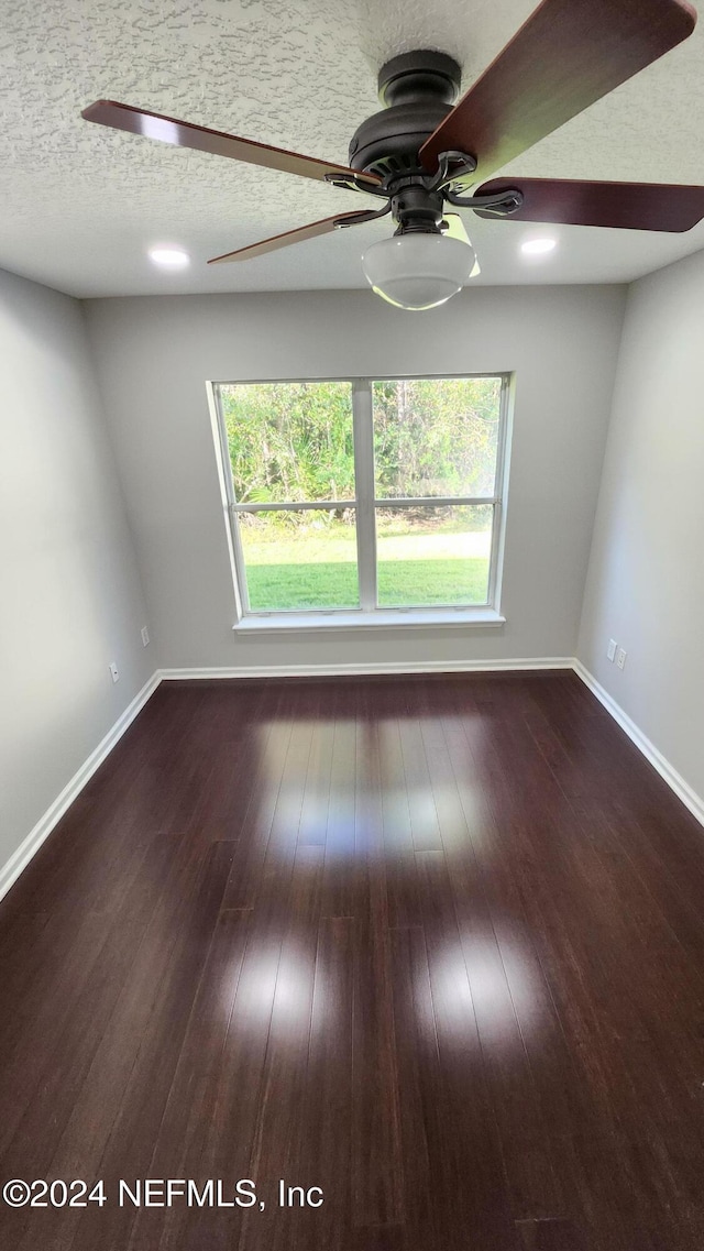 unfurnished room featuring a textured ceiling, plenty of natural light, and dark wood-type flooring