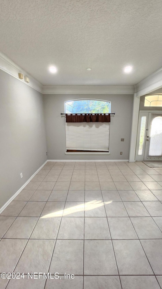 spare room with crown molding, light tile patterned floors, and a textured ceiling