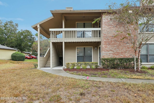 view of front of property with a balcony and a front lawn