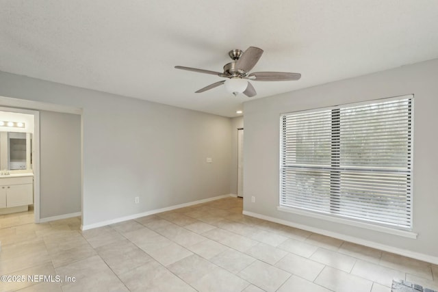 spare room with ceiling fan and light tile patterned flooring