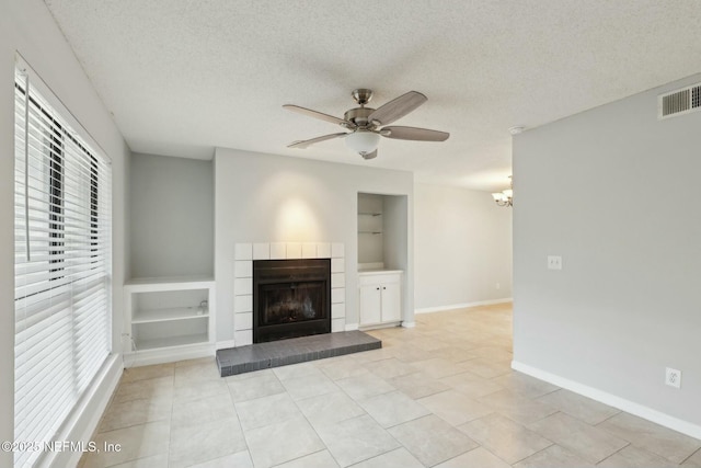 unfurnished living room with ceiling fan with notable chandelier, a textured ceiling, and light tile patterned floors