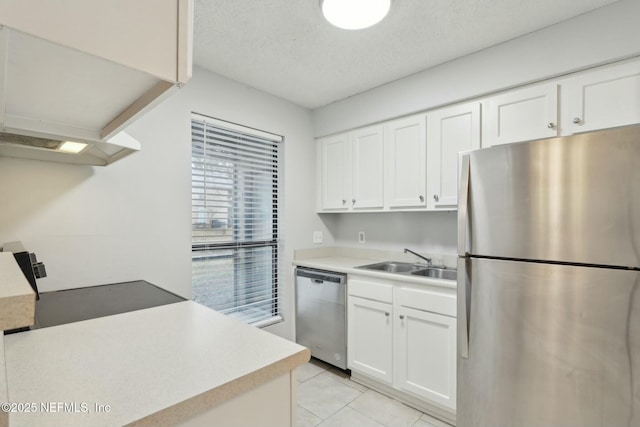 kitchen with sink, white cabinetry, a textured ceiling, light tile patterned floors, and stainless steel appliances