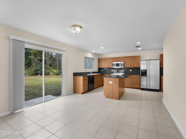 kitchen with a center island, sink, decorative backsplash, light tile patterned floors, and appliances with stainless steel finishes