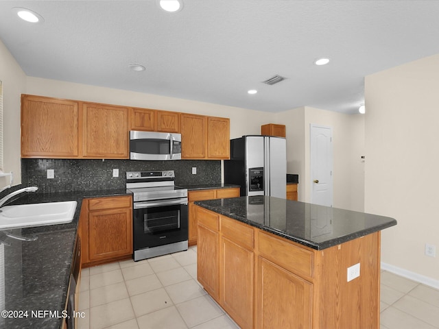 kitchen featuring sink, a center island, tasteful backsplash, dark stone countertops, and appliances with stainless steel finishes