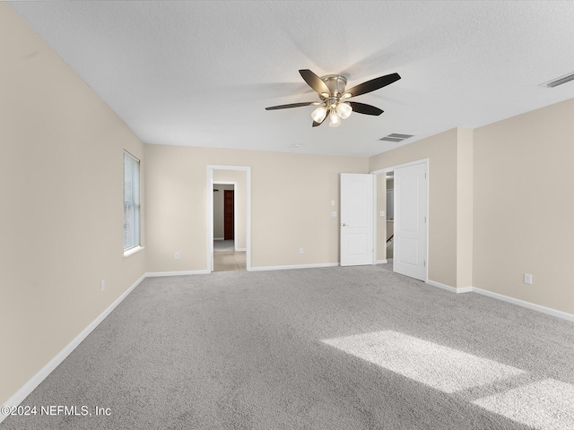 carpeted spare room featuring ceiling fan and a textured ceiling