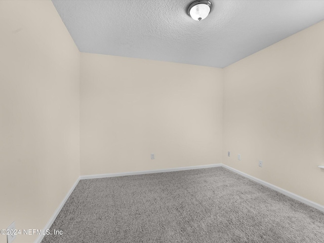 empty room with carpet and a textured ceiling