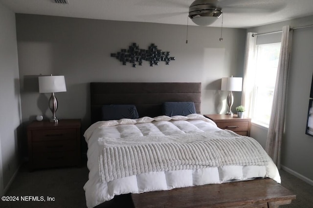 bedroom featuring ceiling fan, dark carpet, and multiple windows