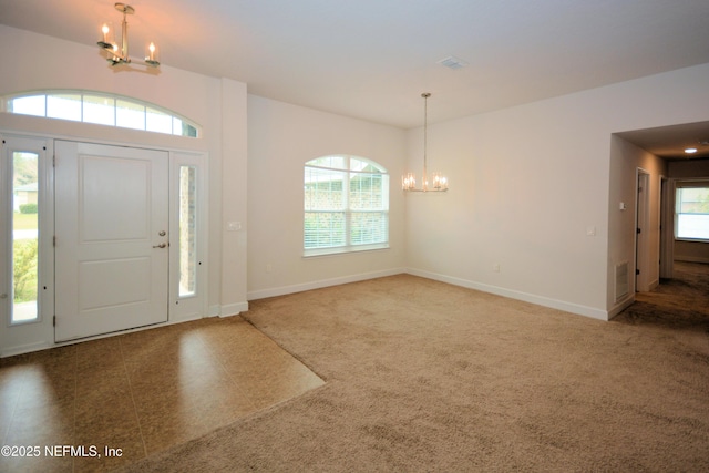 carpeted foyer with an inviting chandelier