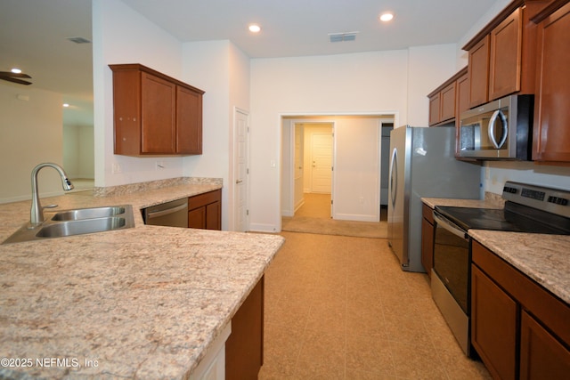 kitchen featuring sink, stainless steel appliances, kitchen peninsula, and light stone countertops