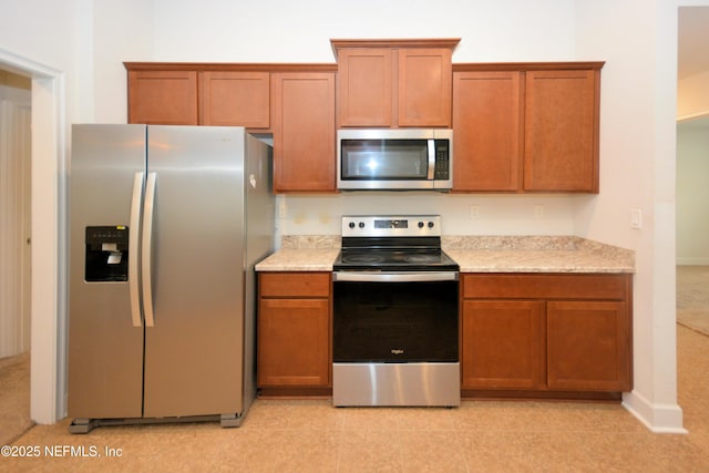 kitchen with appliances with stainless steel finishes and light stone counters