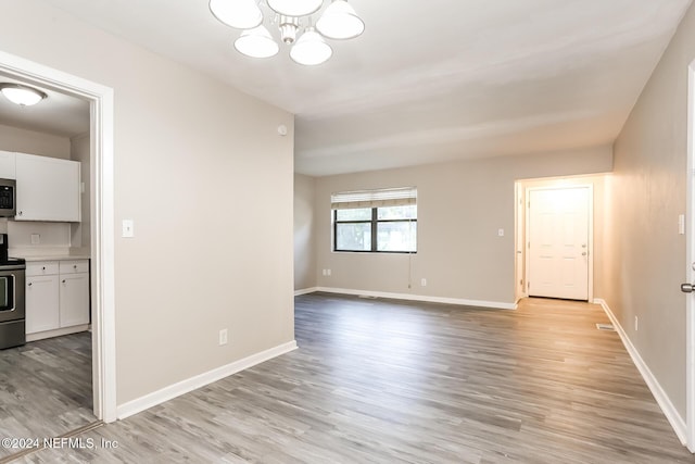 spare room with light hardwood / wood-style flooring and a chandelier