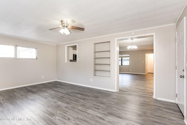 empty room featuring ceiling fan with notable chandelier, built in features, and dark wood-type flooring