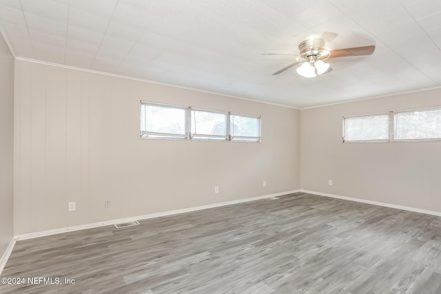 empty room featuring hardwood / wood-style floors, ceiling fan, a healthy amount of sunlight, and ornamental molding