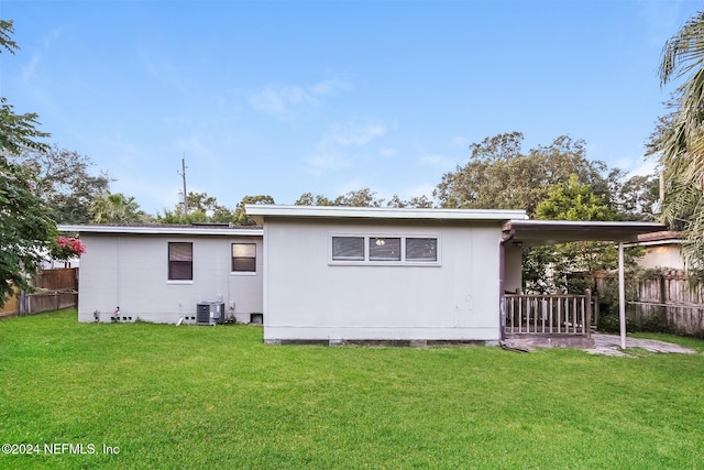 back of property featuring central AC, a yard, and a carport