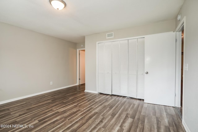 unfurnished bedroom with dark hardwood / wood-style flooring and a closet