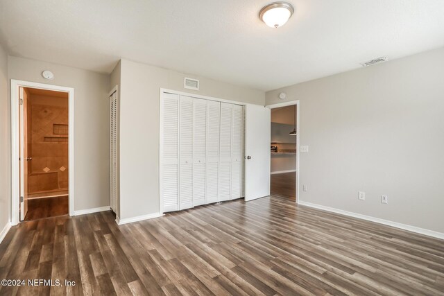 unfurnished bedroom featuring dark hardwood / wood-style floors and ensuite bath