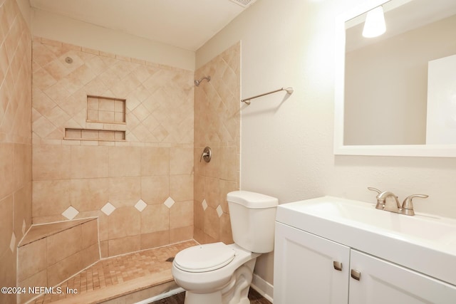 bathroom with vanity, toilet, and tiled shower