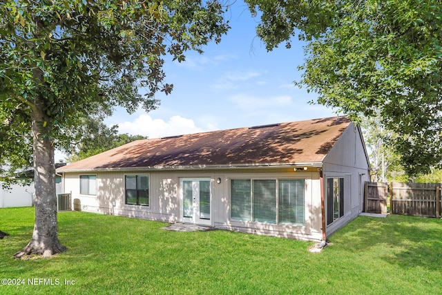 back of property with french doors, cooling unit, and a lawn