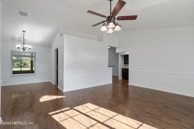 empty room featuring ceiling fan with notable chandelier, dark hardwood / wood-style flooring, and vaulted ceiling