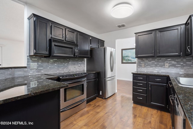 kitchen with stainless steel appliances, light hardwood / wood-style flooring, tasteful backsplash, and dark stone counters