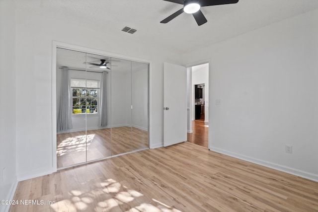 unfurnished bedroom with ceiling fan, light wood-type flooring, a textured ceiling, and a closet