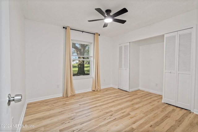 unfurnished bedroom with a textured ceiling, a closet, light hardwood / wood-style flooring, and ceiling fan