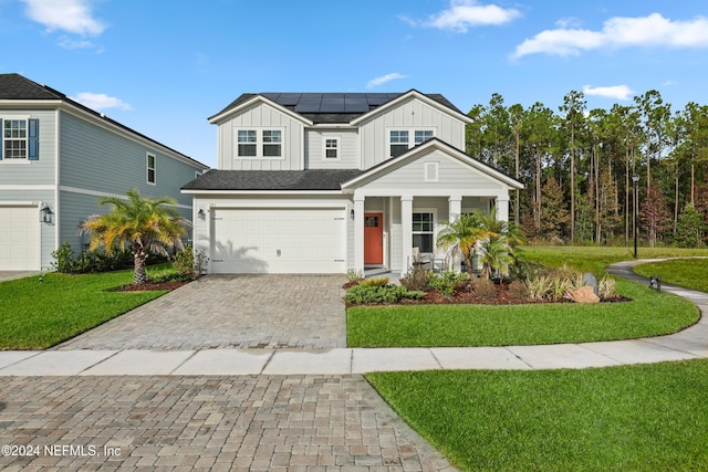 view of front facade with a front yard, solar panels, a garage, and covered porch