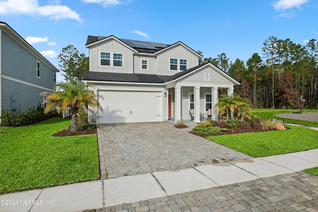 view of front of property with a front yard, a garage, a porch, and solar panels