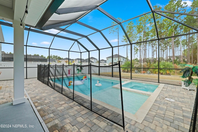 view of pool with glass enclosure, an in ground hot tub, and a patio