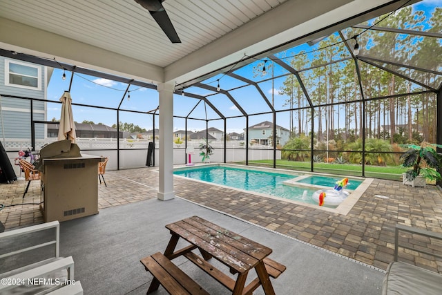 view of swimming pool featuring an in ground hot tub, glass enclosure, ceiling fan, and a patio area