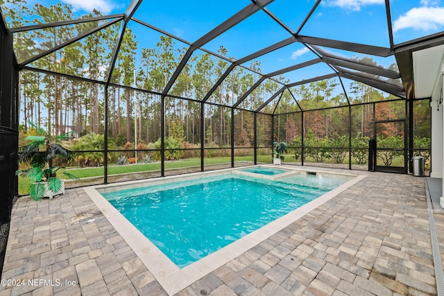 view of swimming pool with an in ground hot tub, a patio, and glass enclosure