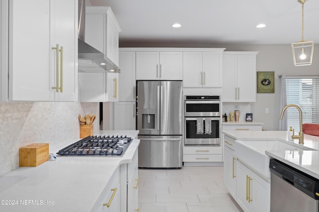 kitchen featuring white cabinetry, pendant lighting, wall chimney range hood, and appliances with stainless steel finishes