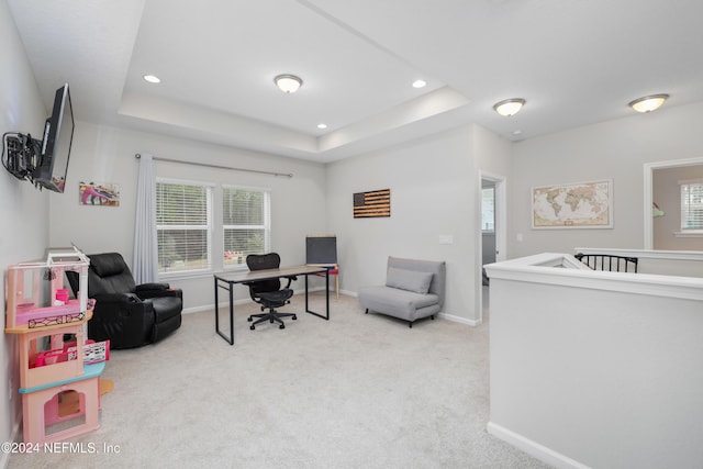 carpeted office featuring a tray ceiling