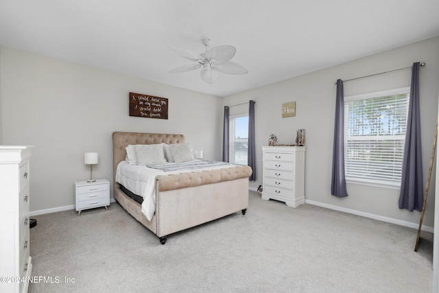 bedroom with multiple windows, ceiling fan, and light colored carpet