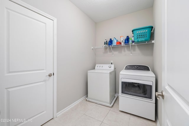 laundry room with independent washer and dryer, a textured ceiling, and light tile patterned floors