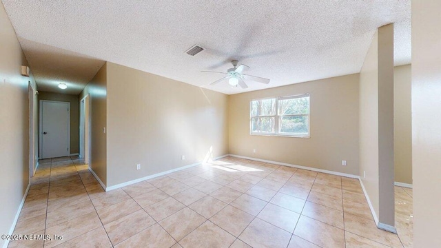 spare room featuring a ceiling fan, visible vents, baseboards, and light tile patterned floors