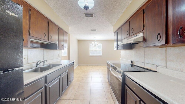 kitchen with under cabinet range hood, a sink, visible vents, light countertops, and appliances with stainless steel finishes