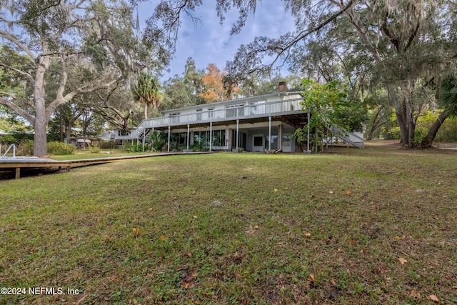 back of house featuring a lawn and a deck