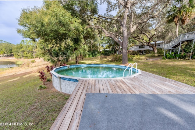 view of pool with a lawn and a deck with water view