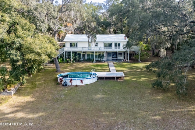 rear view of house with a swimming pool side deck and a yard