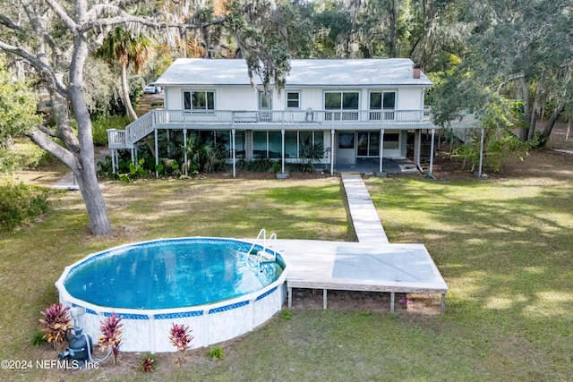 rear view of property with a swimming pool side deck, a yard, and a patio