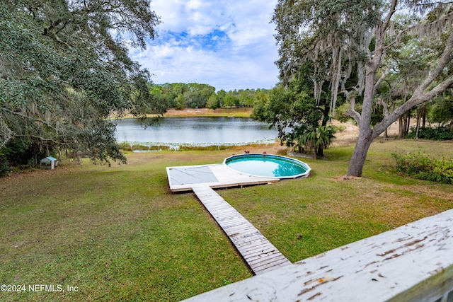 view of swimming pool with a water view and a yard