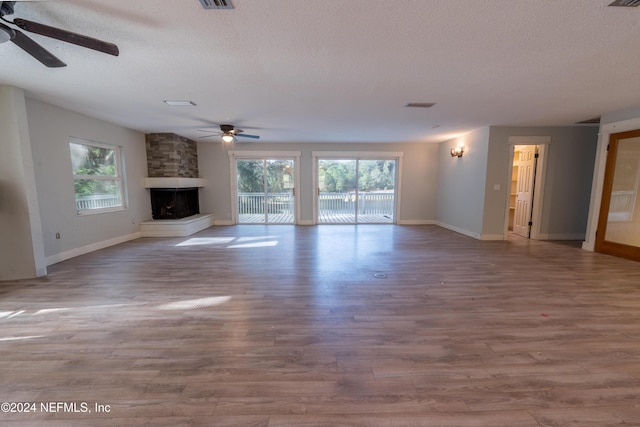 unfurnished living room featuring a large fireplace, light hardwood / wood-style floors, and a textured ceiling