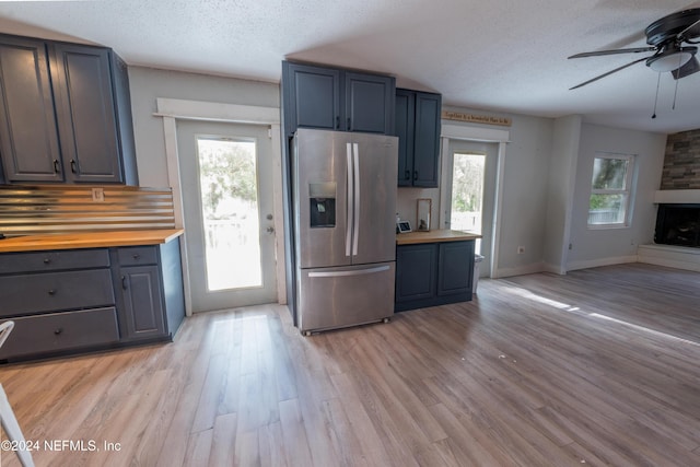 kitchen with a textured ceiling, butcher block counters, a healthy amount of sunlight, and stainless steel refrigerator with ice dispenser