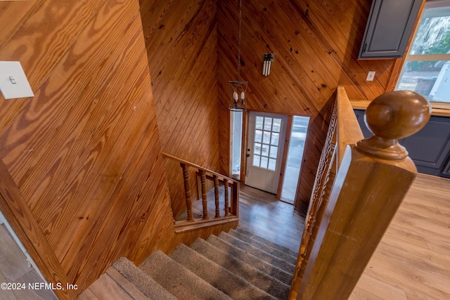 staircase with wood-type flooring, a towering ceiling, a wealth of natural light, and wood walls