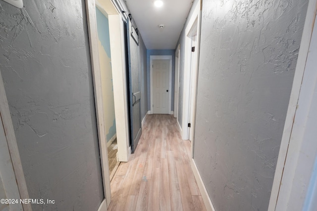 hall featuring a barn door and light hardwood / wood-style flooring